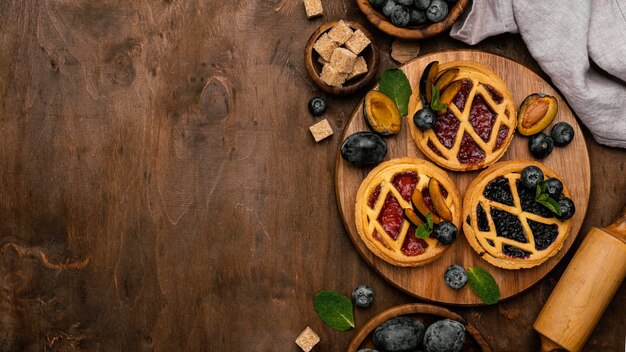 Flat lay of delicious fruit pies with plums and copy space