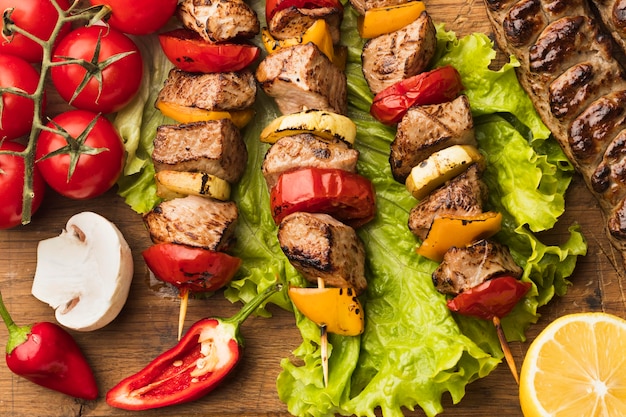 Flat lay of delicious kebab with lemon and tomatoes