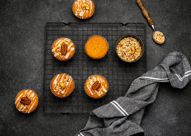 Foto gratuita lay piatto di deliziosi muffin con noci sulla griglia di raffreddamento