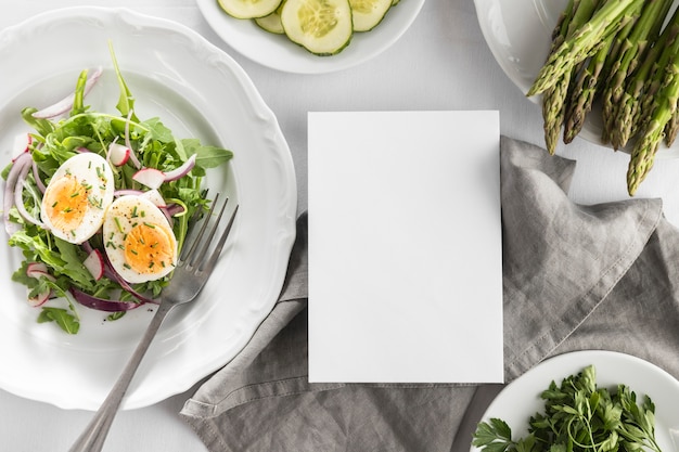 空のカードと白い皿の上にフラットレイおいしいサラダ