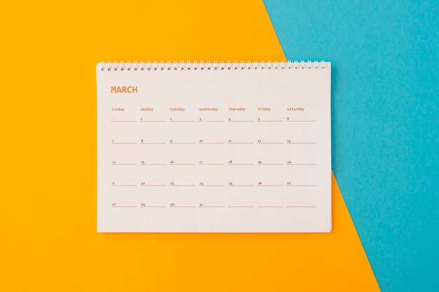 Flat lay desk calendar on yellow and blue background