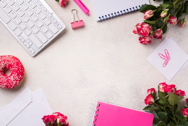 Flat lay of desk with keyboard and bouquet of roses