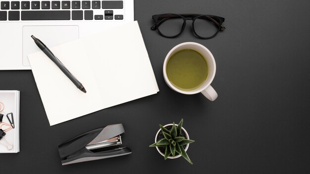 Flat lay of desktop with cup of tea and laptop