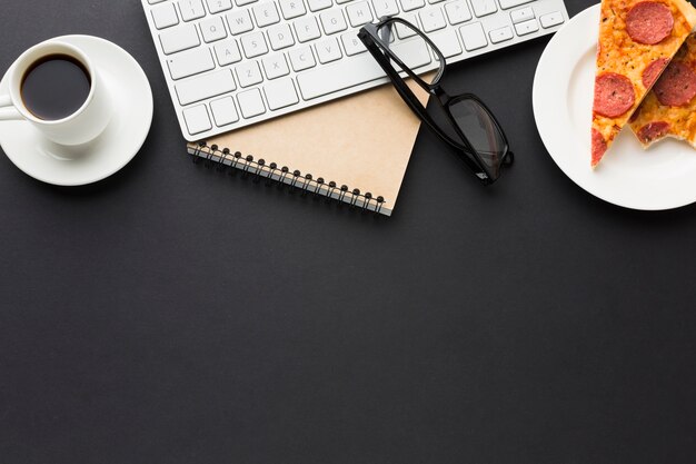 Flat lay of desktop with notebook and pizza