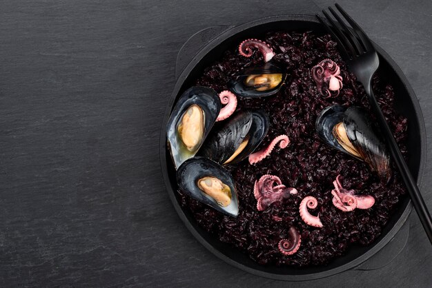 Flat lay of dish with black pasta and mussels