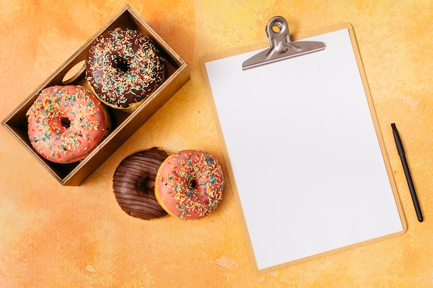 Flat lay donut composition with clipboard