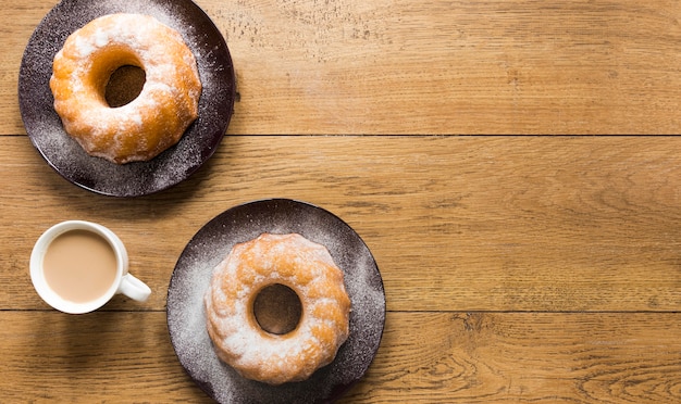 Flat lay of doughnuts on plates with coffee and copy space