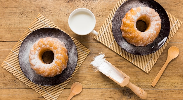 Flat lay of doughnuts on plates with wooden scoop and spoons