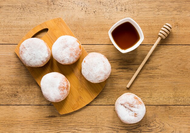 Flat lay of doughnuts with honey dipper