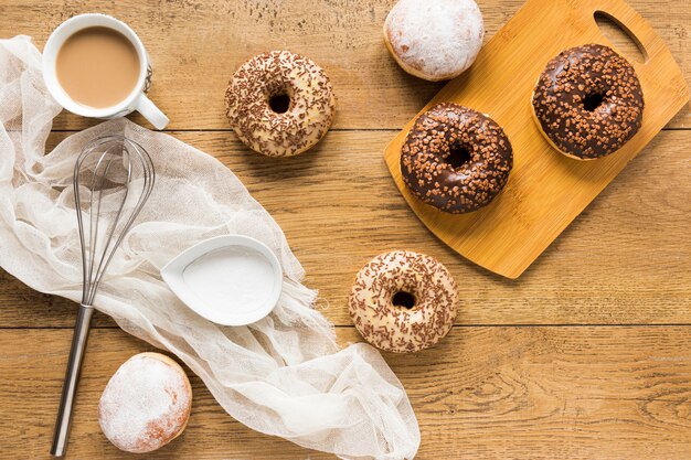 Flat lay of doughnuts with sprinkles on wooden surface