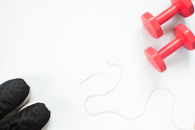 Flat lay of earphone, red dumbbells and sport equipment on white background. Sport wear, Sport fashion, Sport accessories, Sport equipment, top view