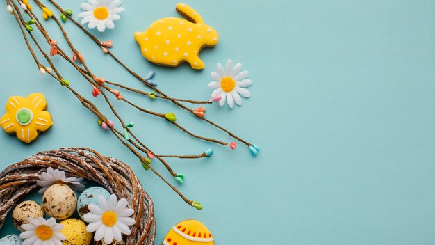 Flat lay of easter eggs in basket with chamomile flowers and bunny