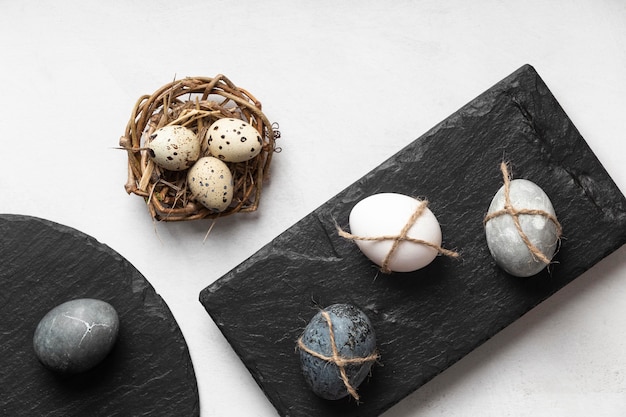 Flat lay of easter eggs in bird nest and slate