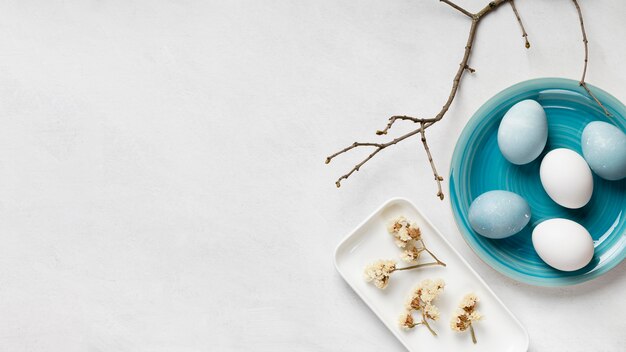 Flat lay of easter eggs on plates with copy space and twig