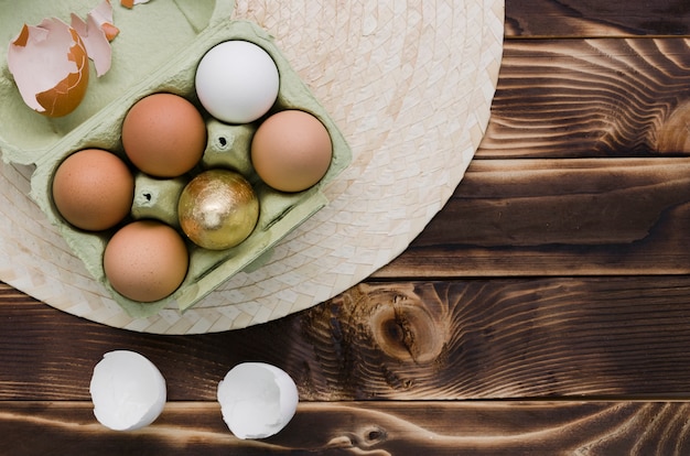 Free photo flat lay of eggs for easter in carton over placemat