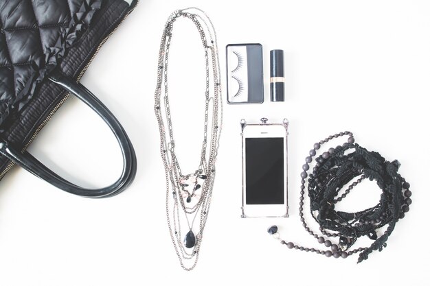 흰색 배경에 고립 된 검은 개념, 평면도, 빈 노트북, 핸드폰 및 여자의 액세서리의 평면 배치