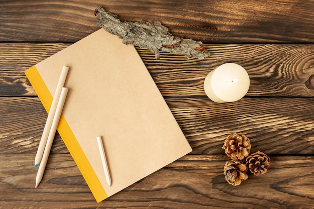 Flat lay empty notebook next to pine cones 