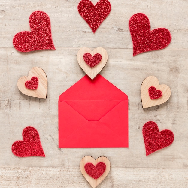 Free photo flat lay of envelope with hearts on wooden background