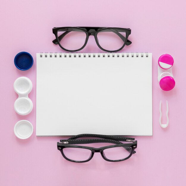 Flat lay eye care accessories on pink background with notebook mock-up