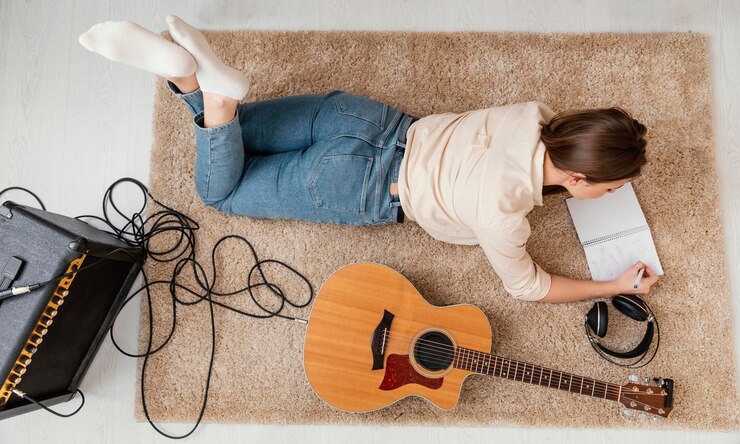 Free Photo flat lay of female musician at home writing song with headphones and acoustic guitar