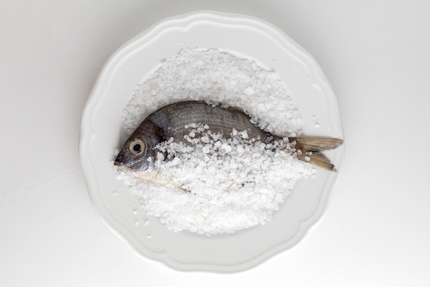 Lay piatto di pesce sulla piastra con sale