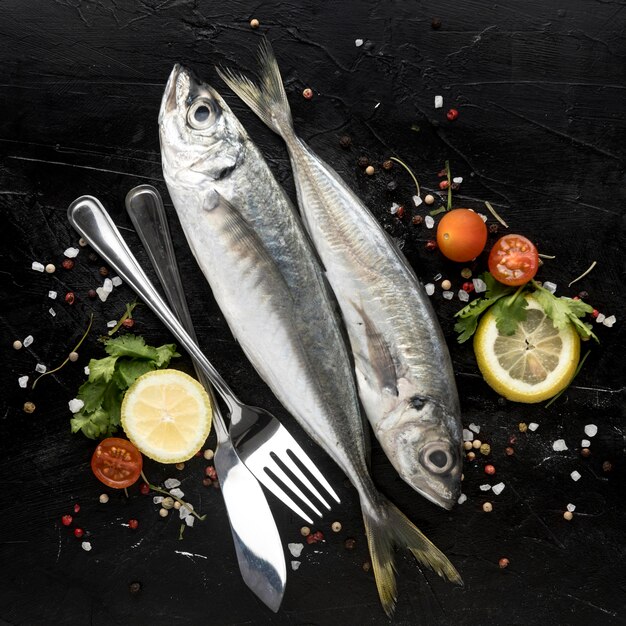 Flat lay of fish with tomatoes and cutlery