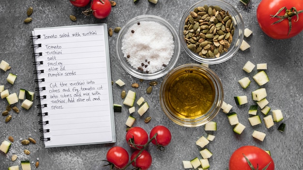 Foto gratuita lay piatto di ingredienti alimentari con olio e taccuino