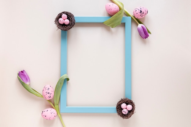 Free photo flat lay frame of flowers and painted eggs