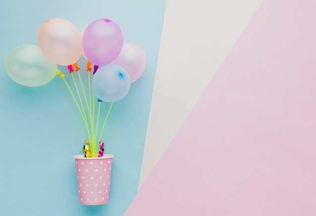 Flat lay frame with colorful balloons and cup