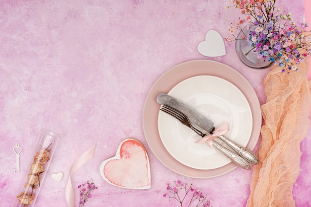 Flat lay frame with plate and cutlery on pink background