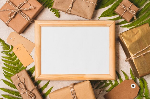 Free photo flat lay of frame with presents and fern