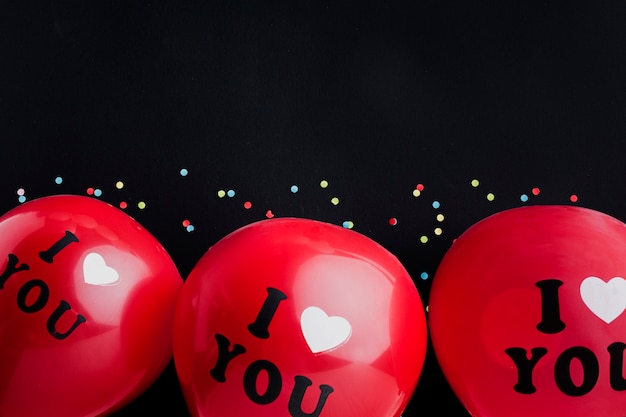 Foto gratuita telaio piatto laico con palloncini rossi e sfondo nero