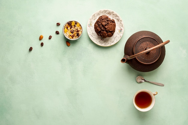 Flat lay frame with teapot and muffin