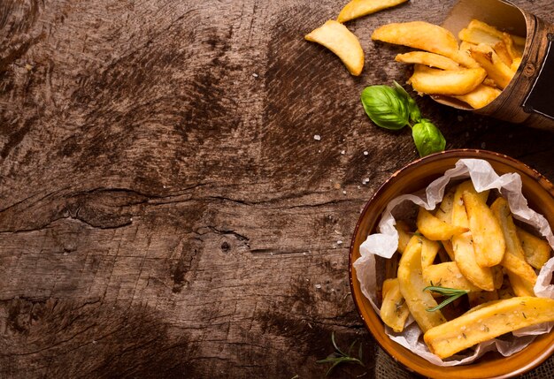 Flat lay of french fries in bowl with herbs and copy space