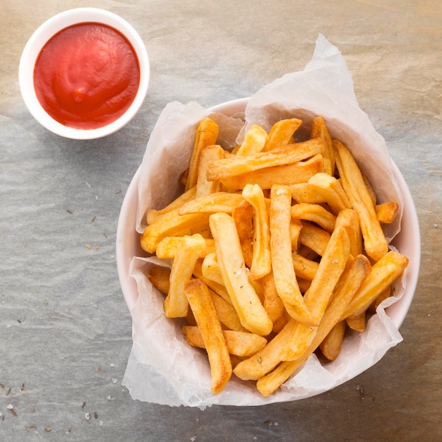 Flat lay of french fries in bowl with ketchup sauce