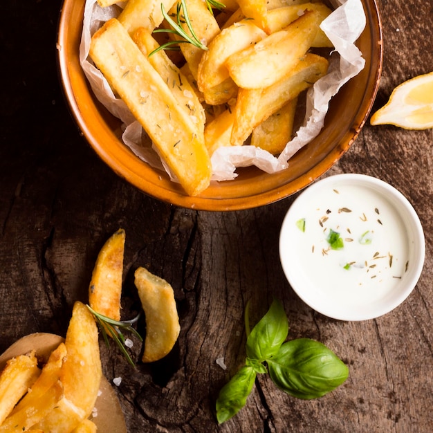 Flat lay of french fries in bowl with special sauce and herbs