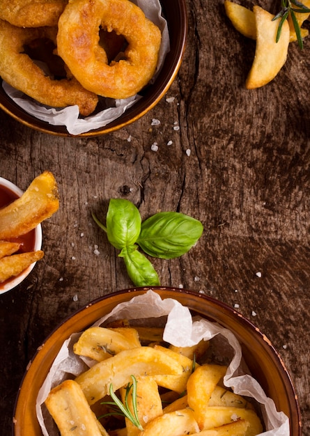 Flat lay of french fries in bowls with salt and herbs