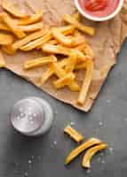 Free photo flat lay of french fries on paper with salt and ketchup