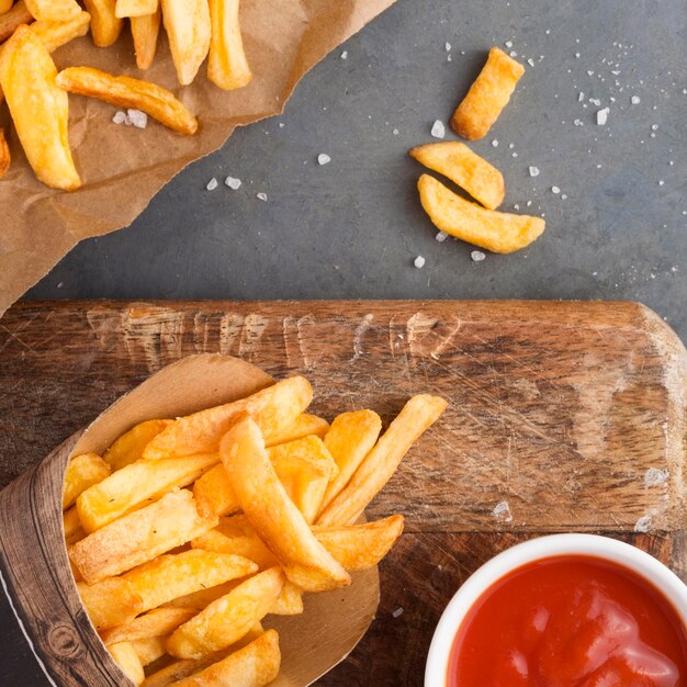 Flat lay of french fries with ketchup and salt