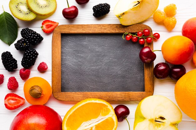 Flat-lay of fresh berries and fruits with blackboard