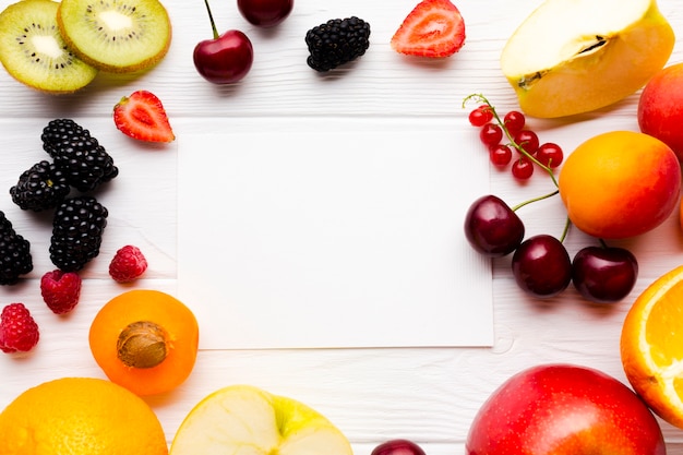 Flat-lay of fresh berries and fruits with paper