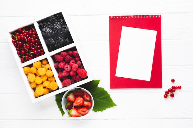 Free photo flat-lay fresh berries with notepad