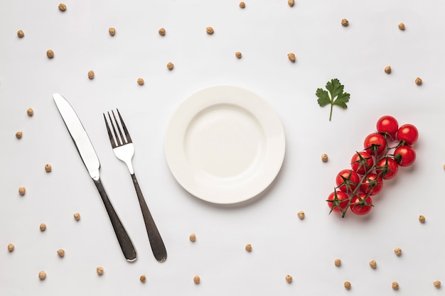 Flat lay of fresh tomatoes with plate and cutlery