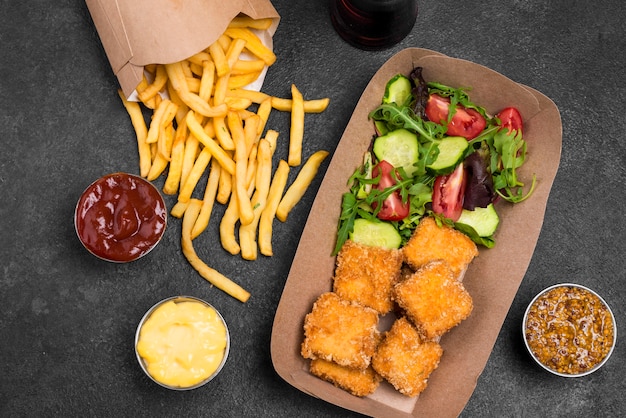 Flat lay of fried chicken nuggets with salad and french fries