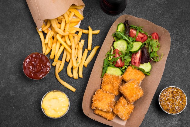 Flat lay of fried chicken nuggets with salad and french fries