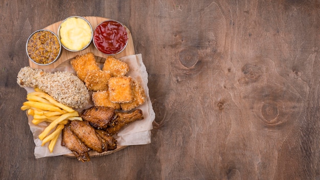 Foto gratuita lay piatto di pollo fritto con diversi tipi di salsa e copia spazio