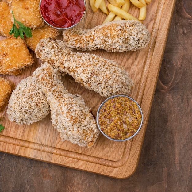 Flat lay of fried chicken with sauce and french fries