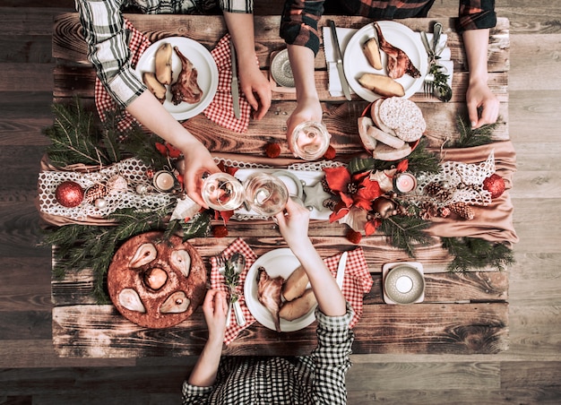 Flat-lay of friends hands eating and drinking together. Top view of people having party, gathering, celebrating together at wooden rustic table