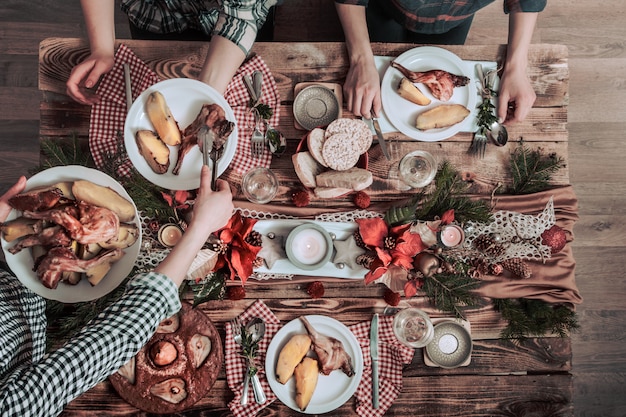 Flat-lay of friends hands eating and drinking together. Top view of people having party, gathering, celebrating together at wooden rustic table