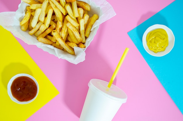 Foto gratuita disposizione piana di patatine fritte e soda su sfondo colorato